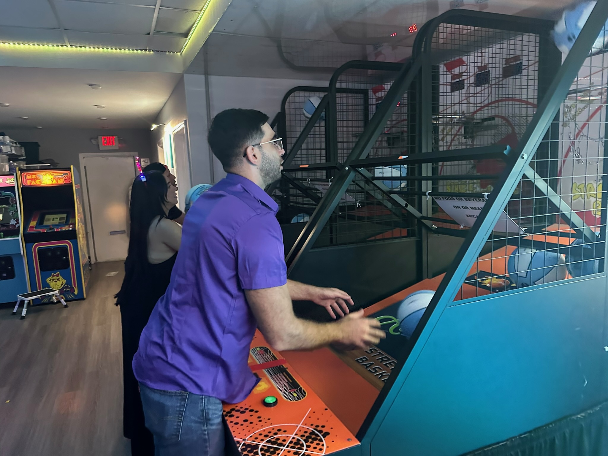 Adult playing street basketball arcade machine at All Star Party World